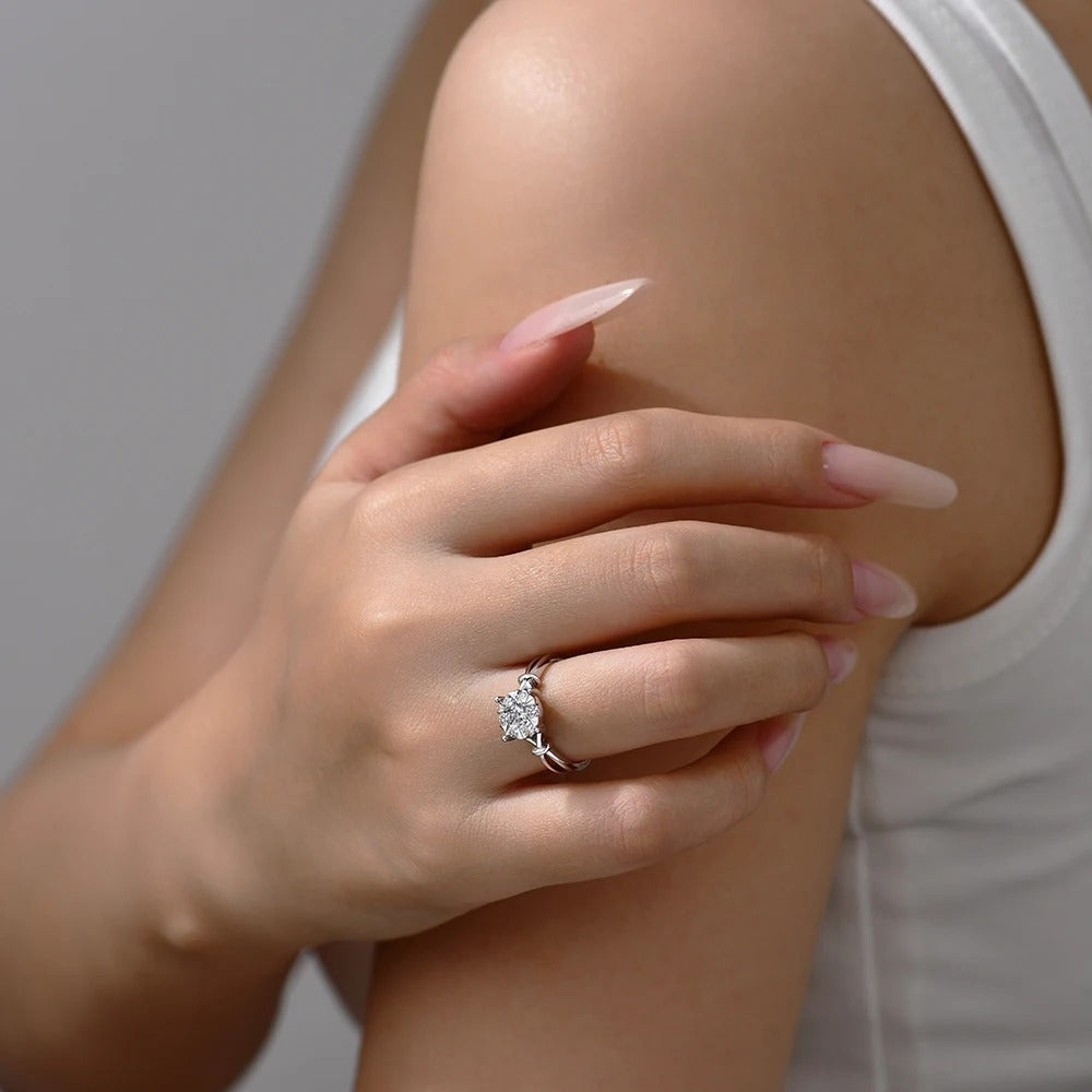 Close-up of a hand wearing a diamond ring on a neutral background