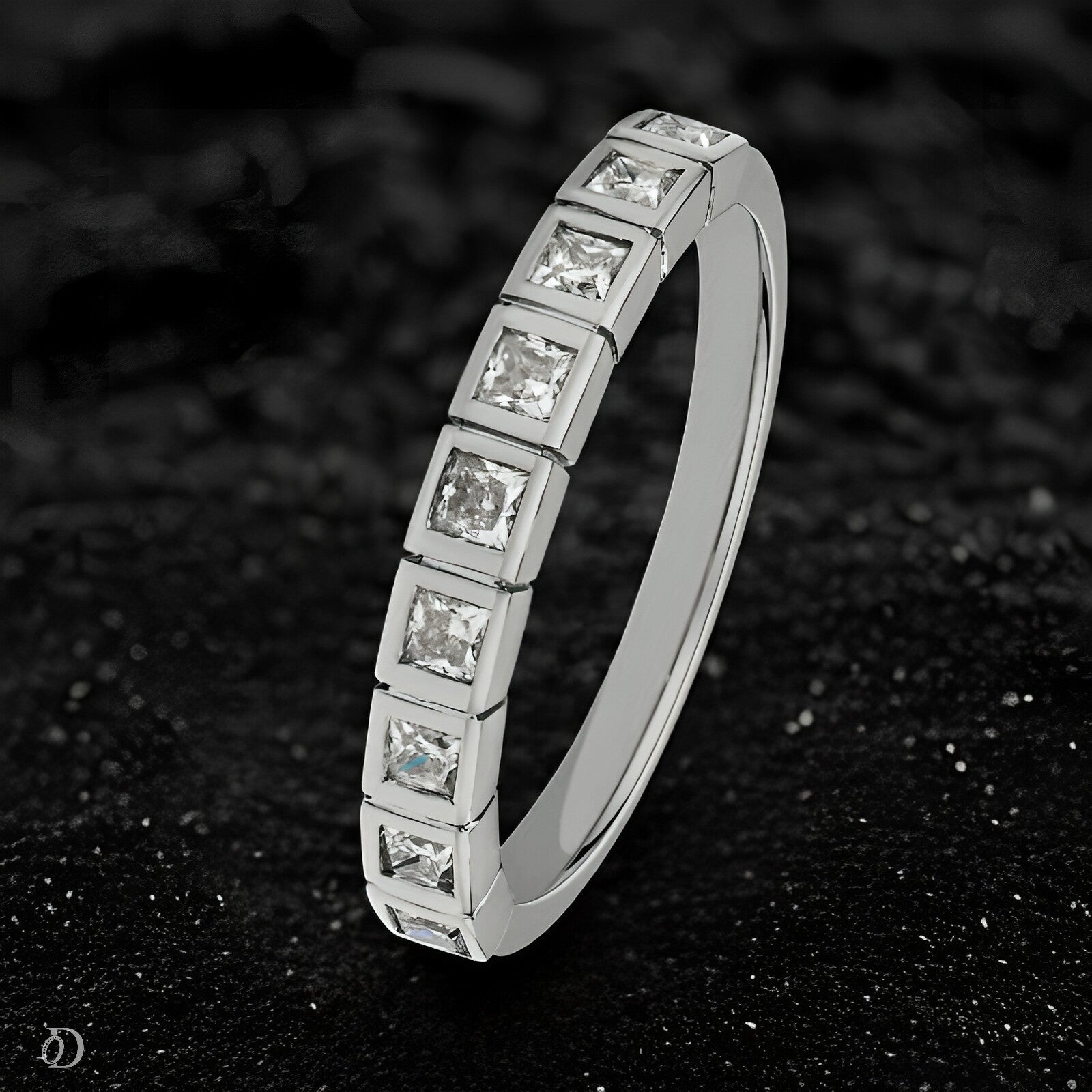 Silver ring with square-cut diamonds on a black textured background