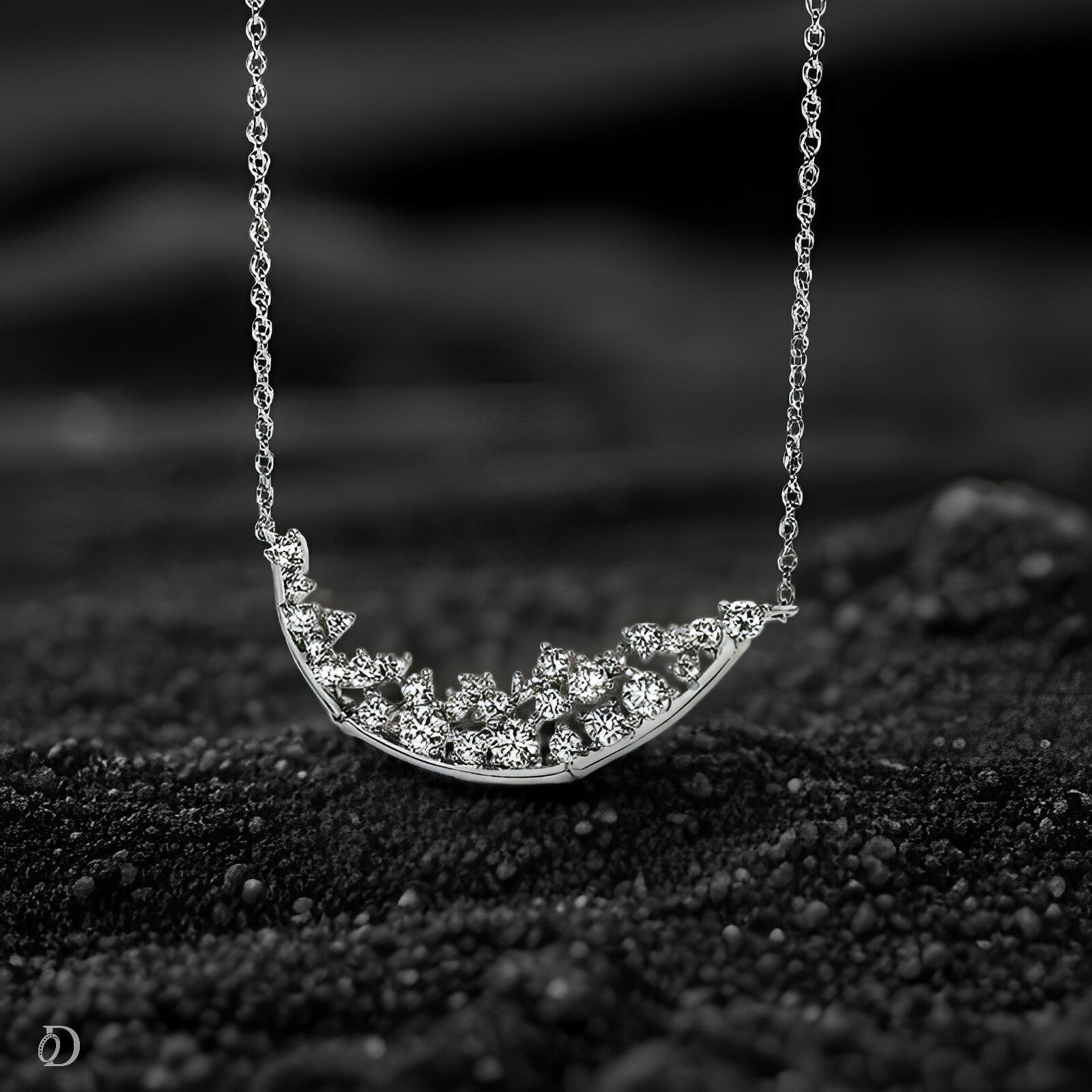Silver necklace with a crescent moon-shaped pendant on a black textured surface