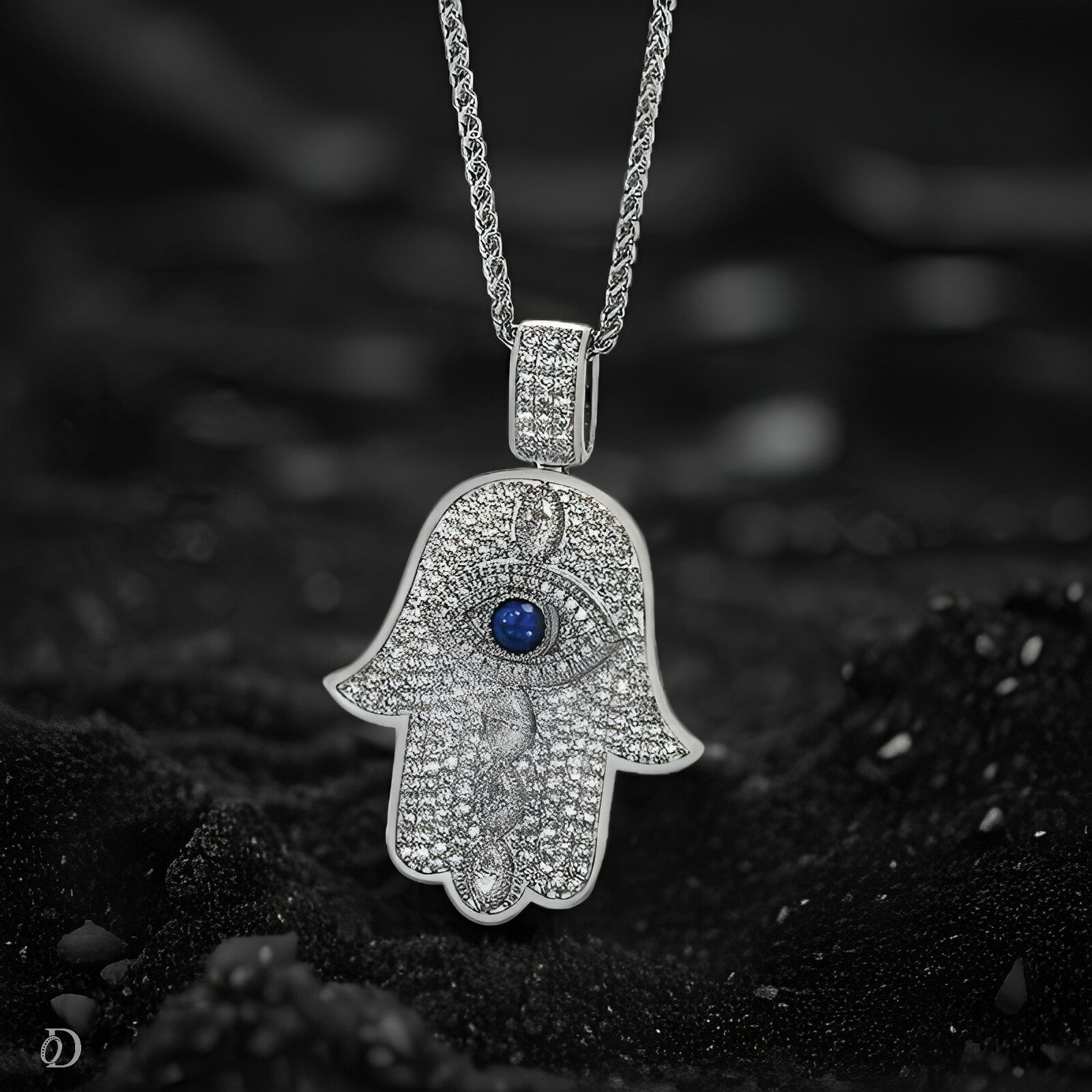 Silver Hamsa hand pendant with a blue gemstone on a dark background