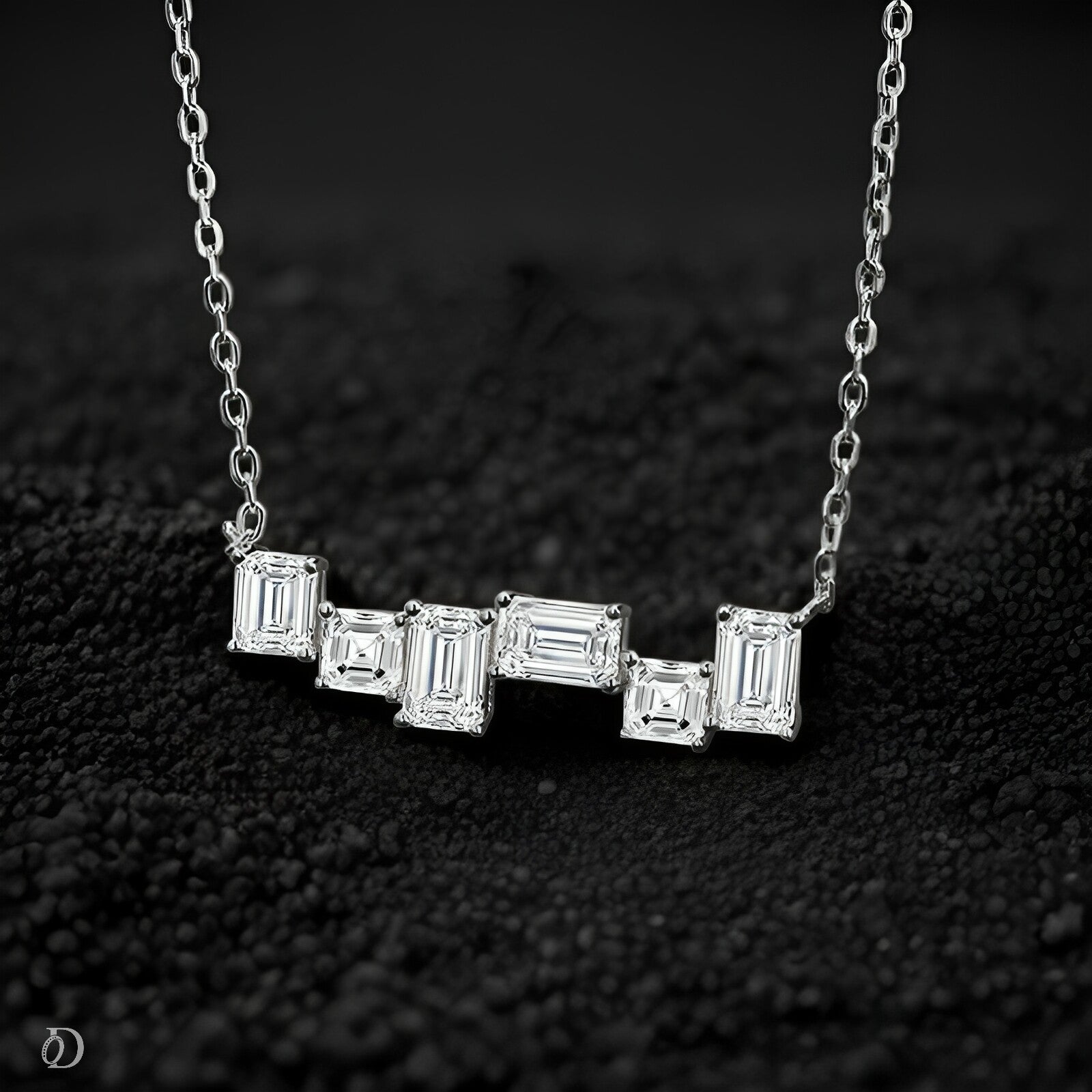 Silver necklace with rectangular diamond pendants on a dark textured background