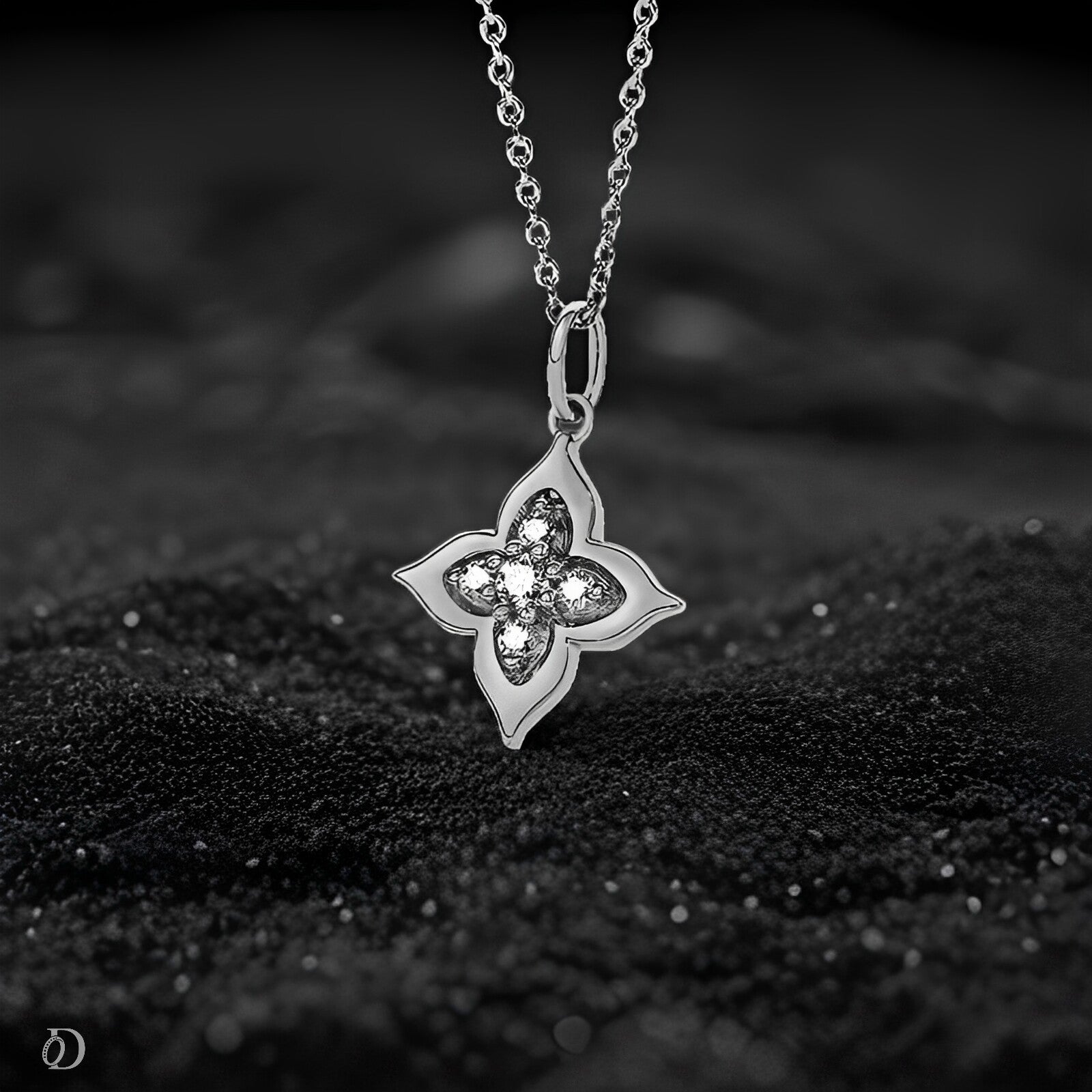 Silver necklace with a clover-shaped pendant on a black textured surface