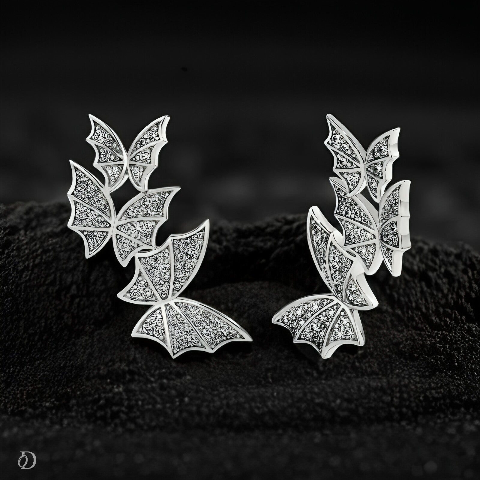 Butterfly-shaped earrings with diamond-like stones on a dark textured surface