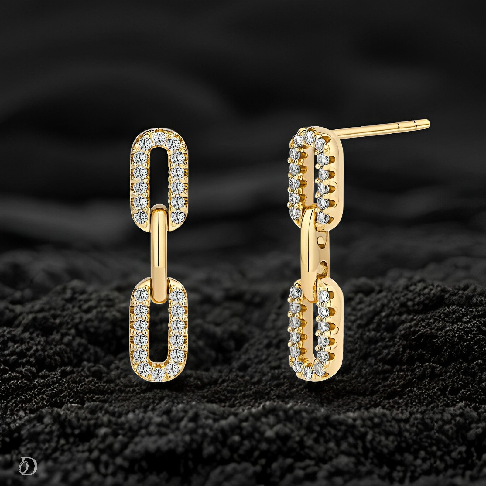 Gold hoop earrings with diamond accents on a textured black surface