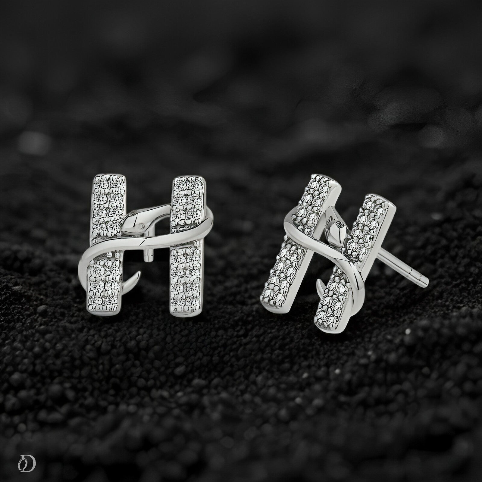 Silver earrings with diamond accents on a black textured background