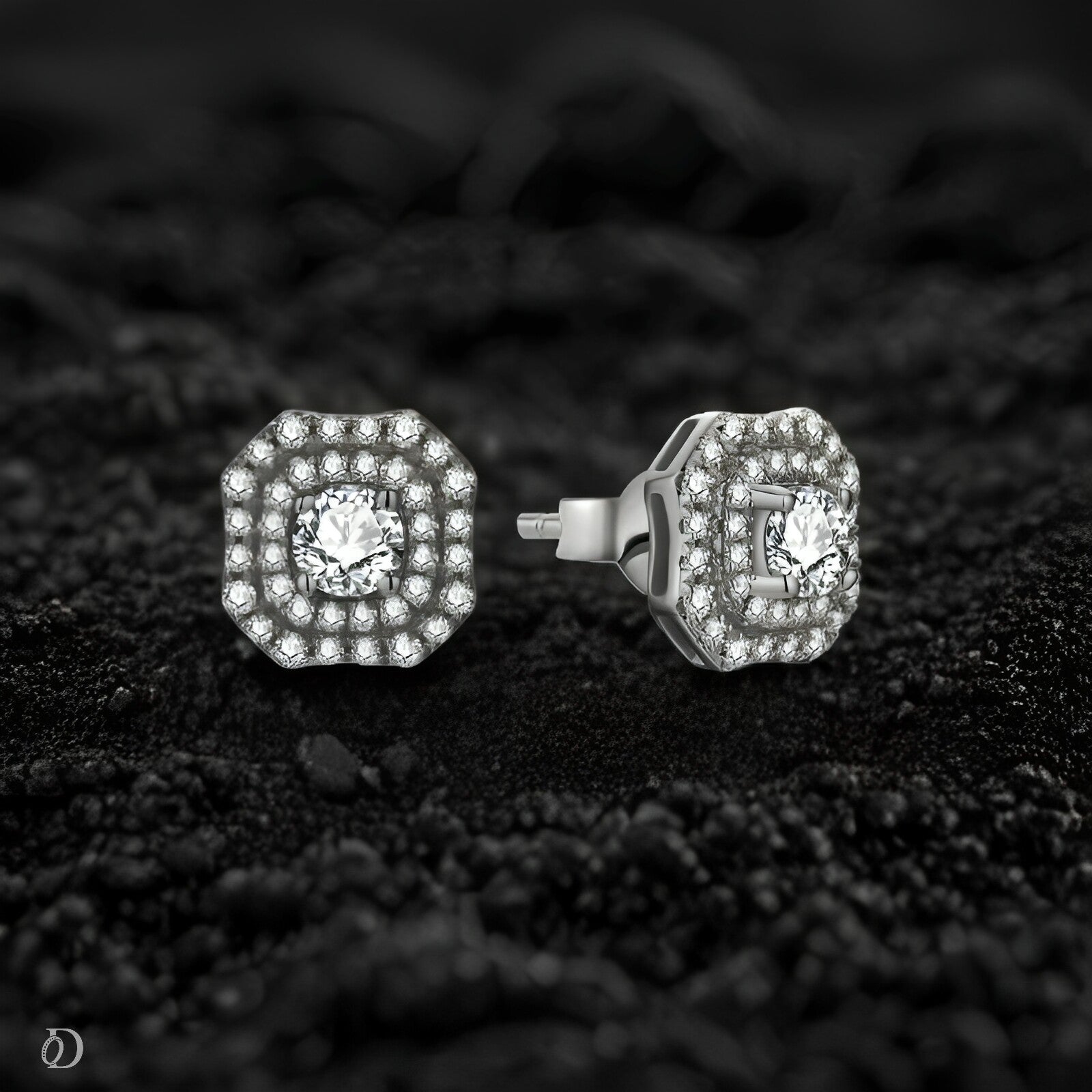 Pair of diamond stud earrings on a textured black surface