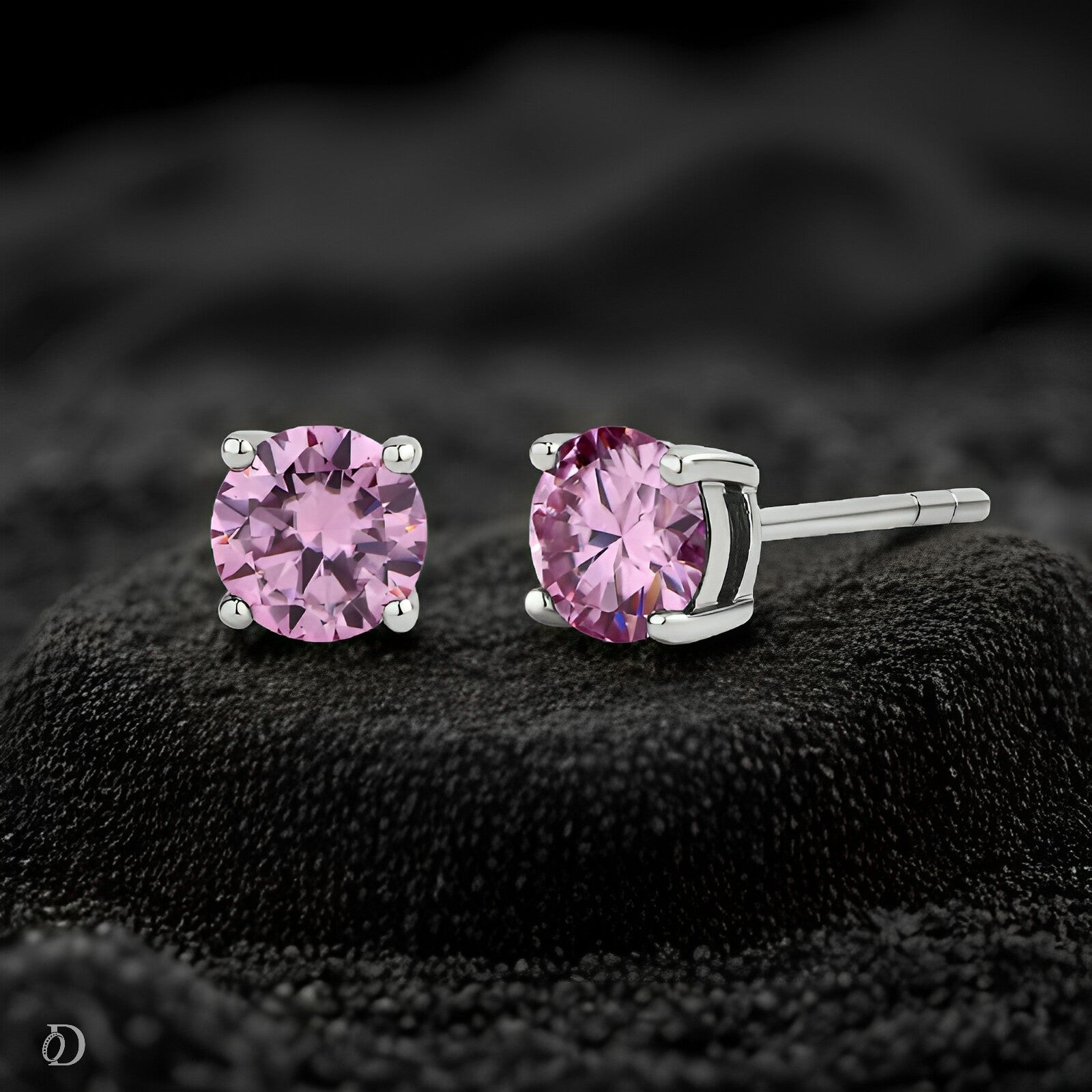 Pink gemstone stud earrings on a black textured surface