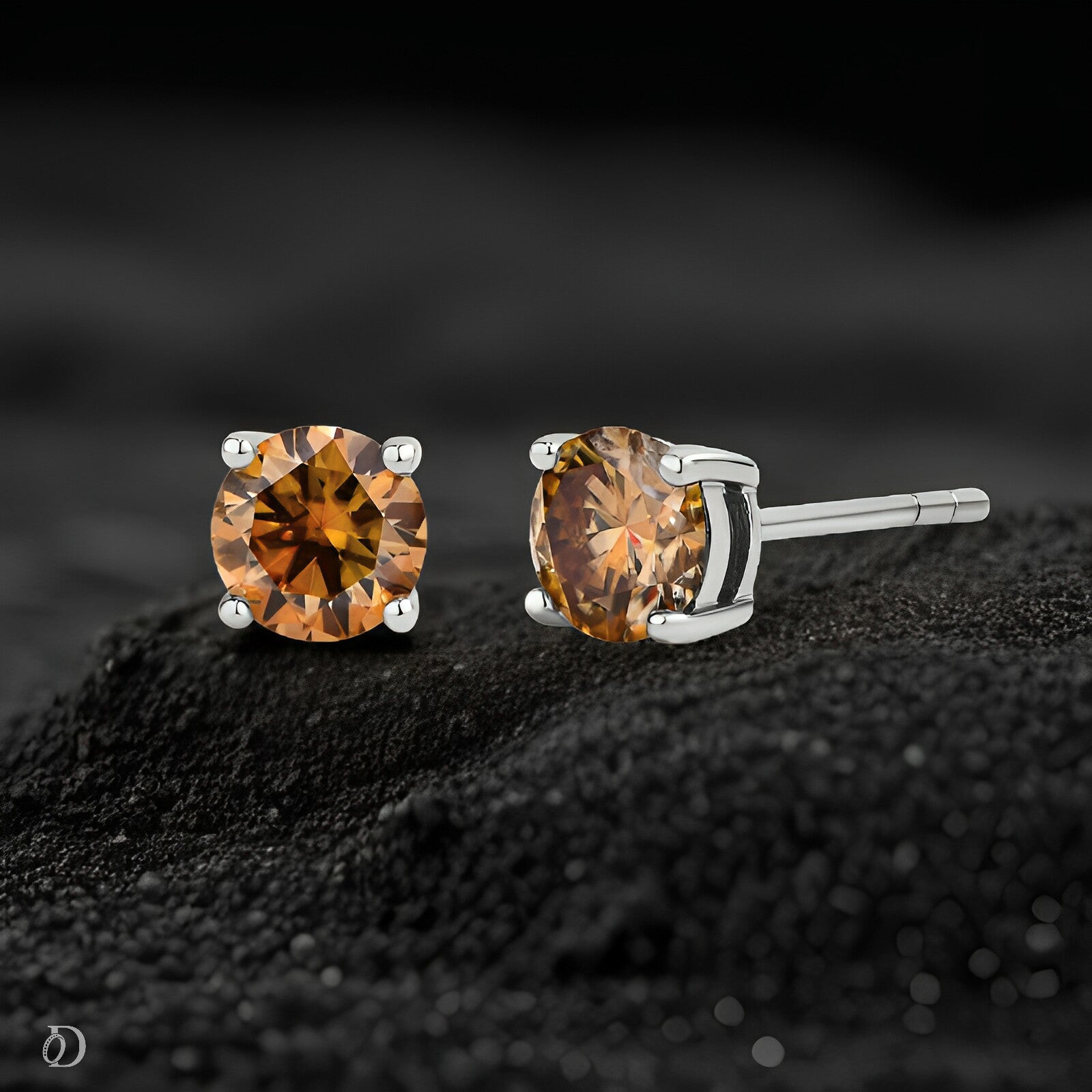 Pair of amber-colored stud earrings on a black textured surface