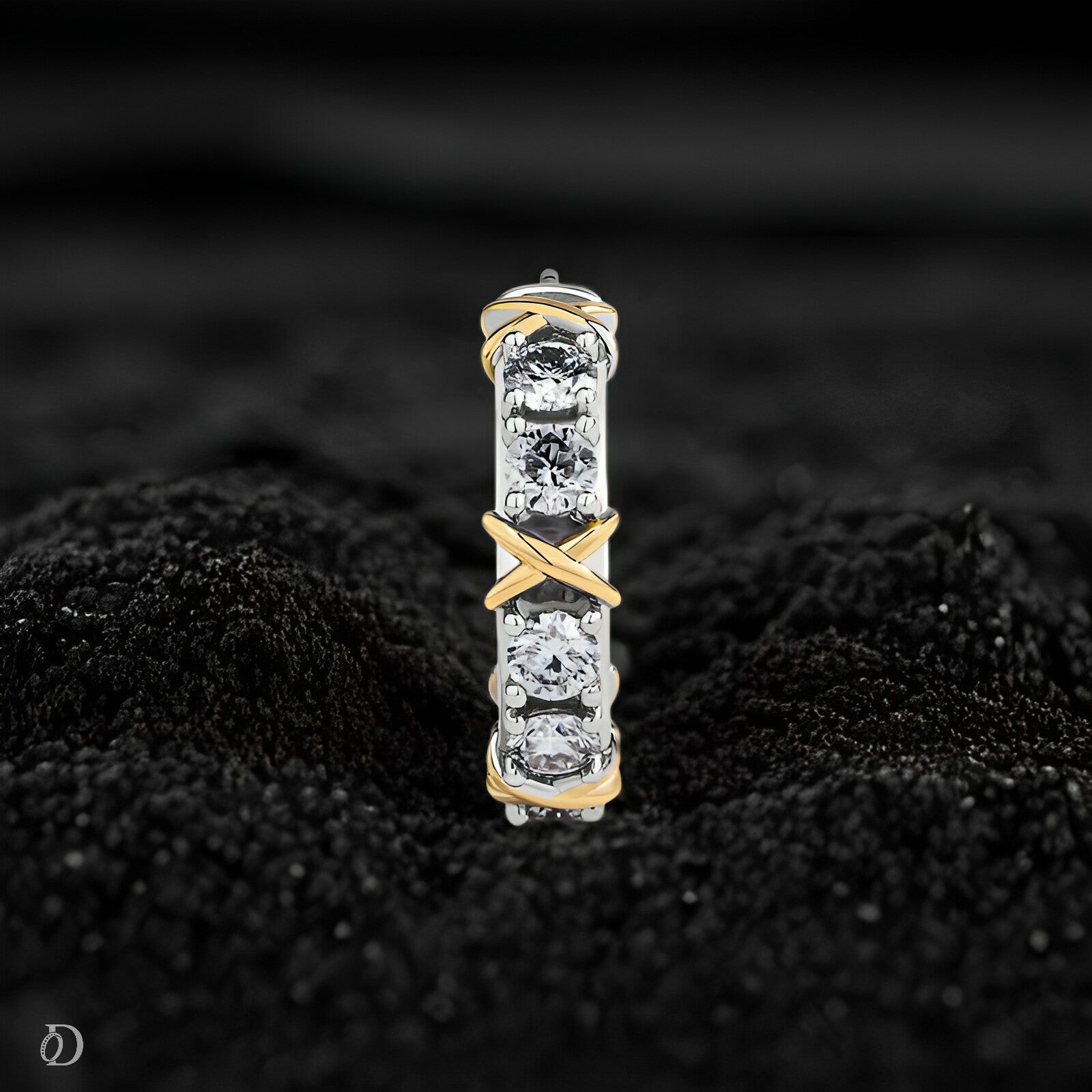 Gold and silver earring with diamonds on a black textured background