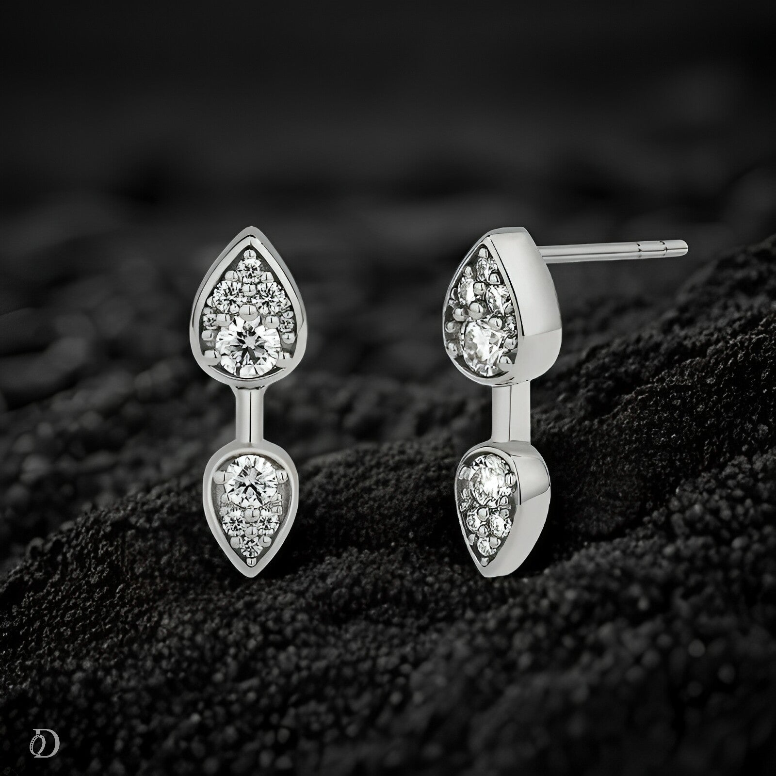 Pair of silver earrings with gemstones on a textured black surface