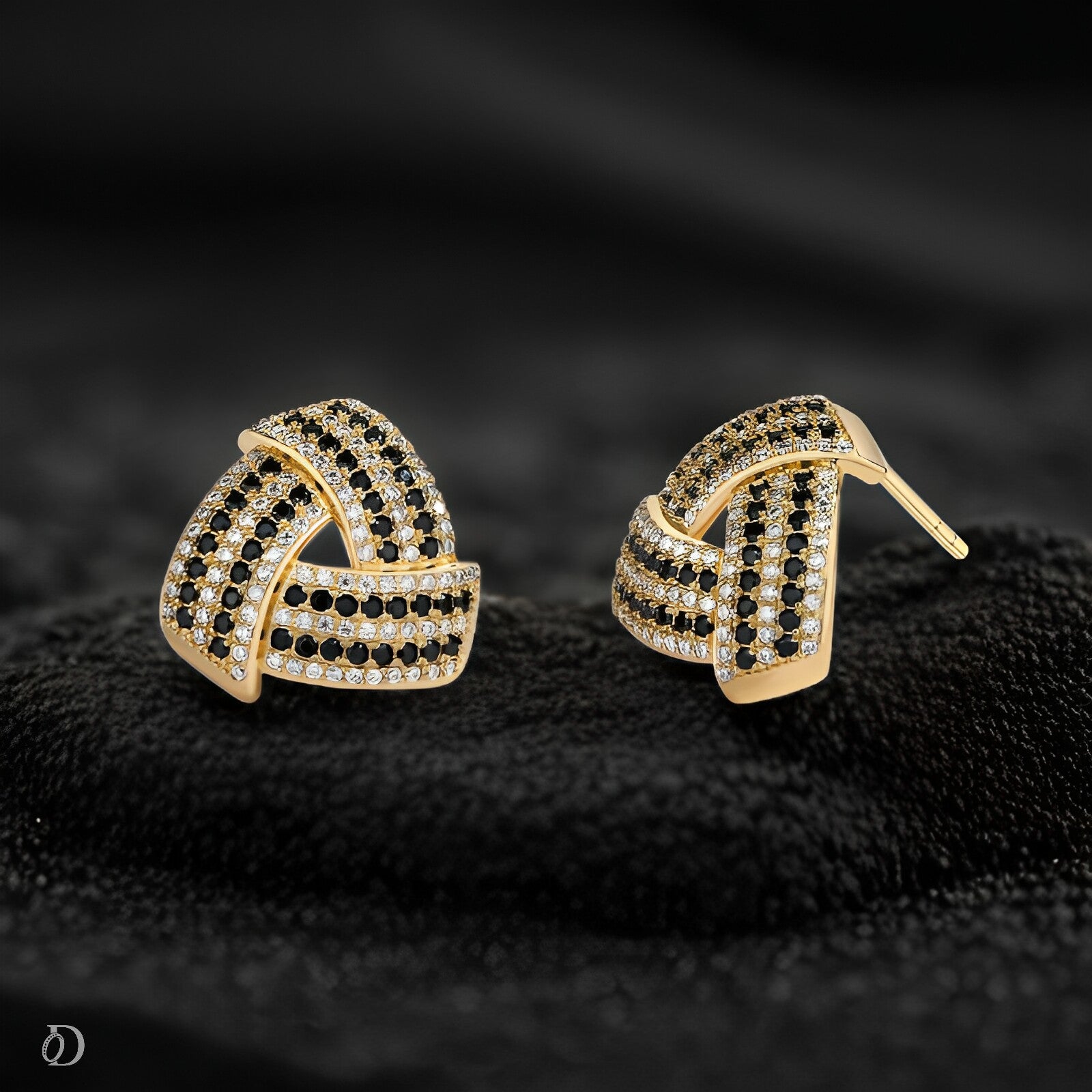 Gold and black earrings on a dark textured surface