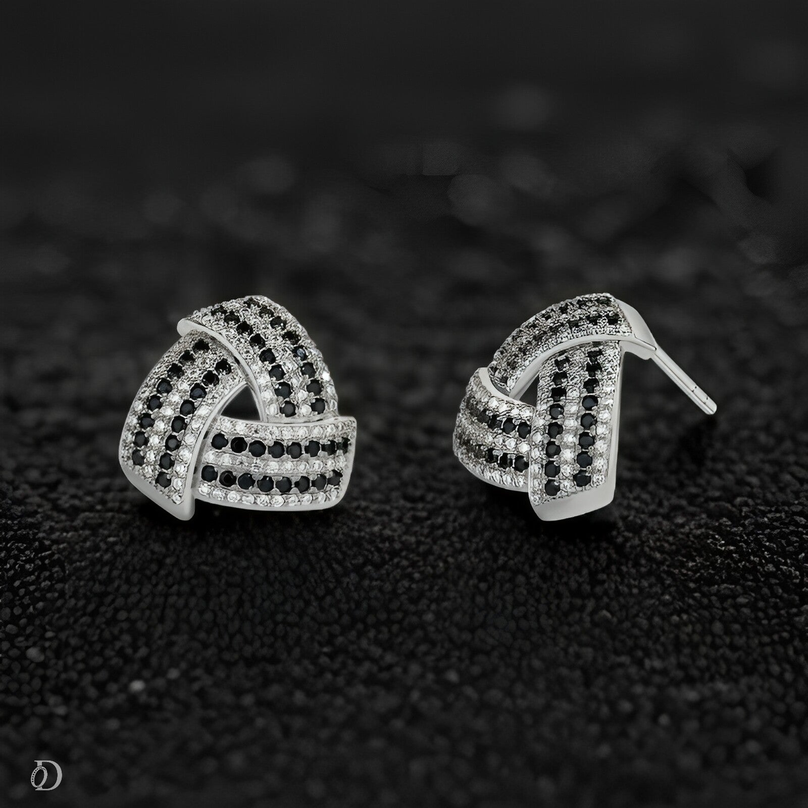 Pair of silver earrings with black and white stones on a dark textured background