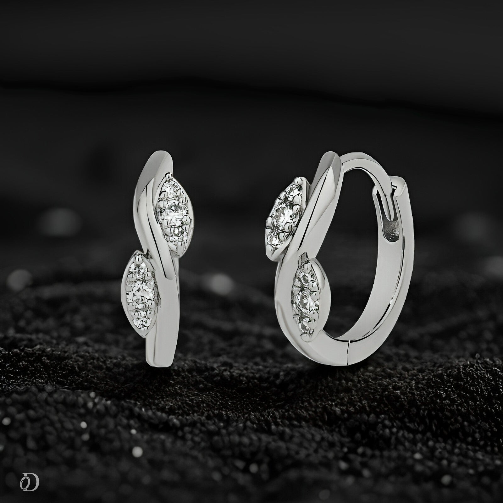 Silver hoop earrings with gemstones on a dark textured surface