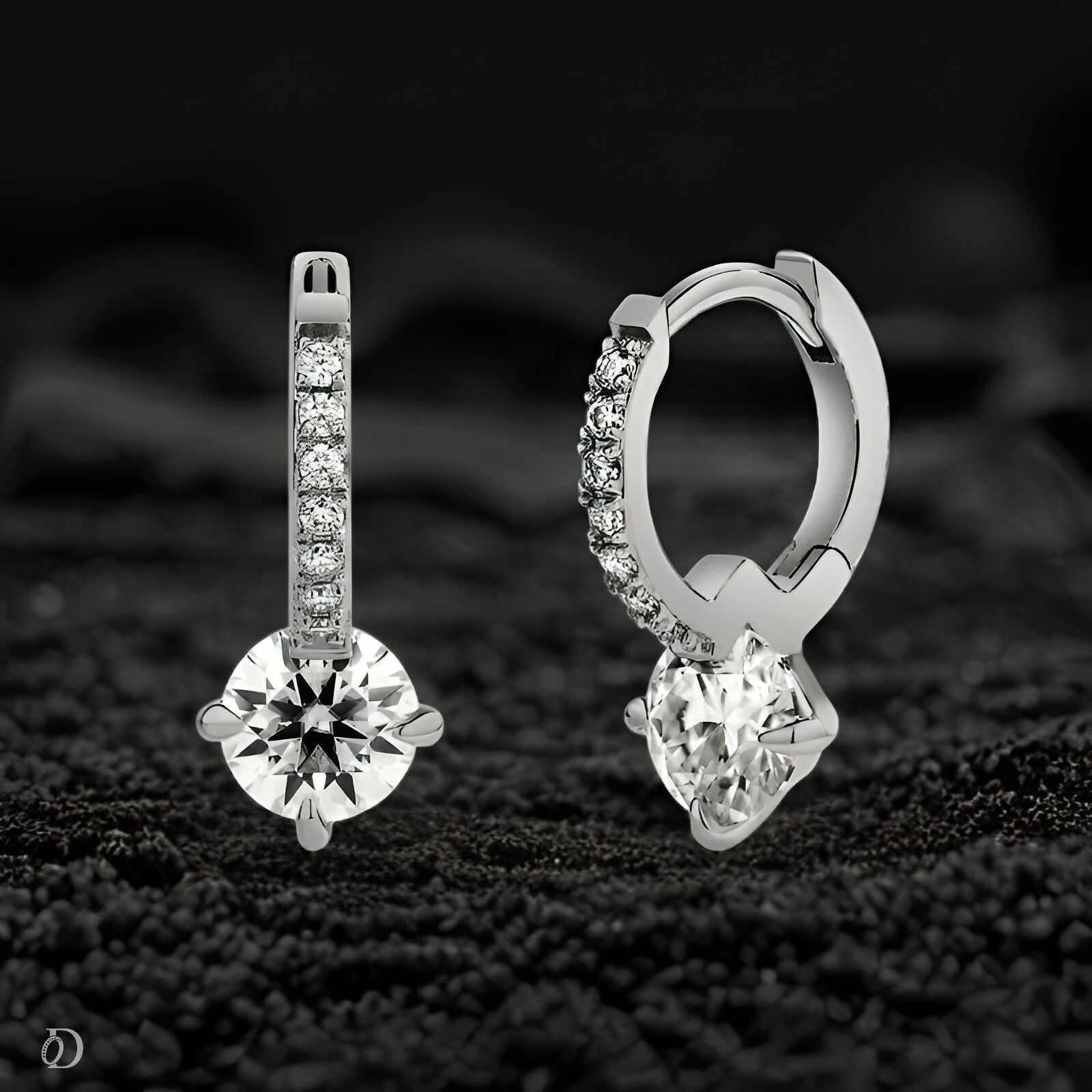 Pair of silver hoop earrings with clear gemstones on a dark textured background