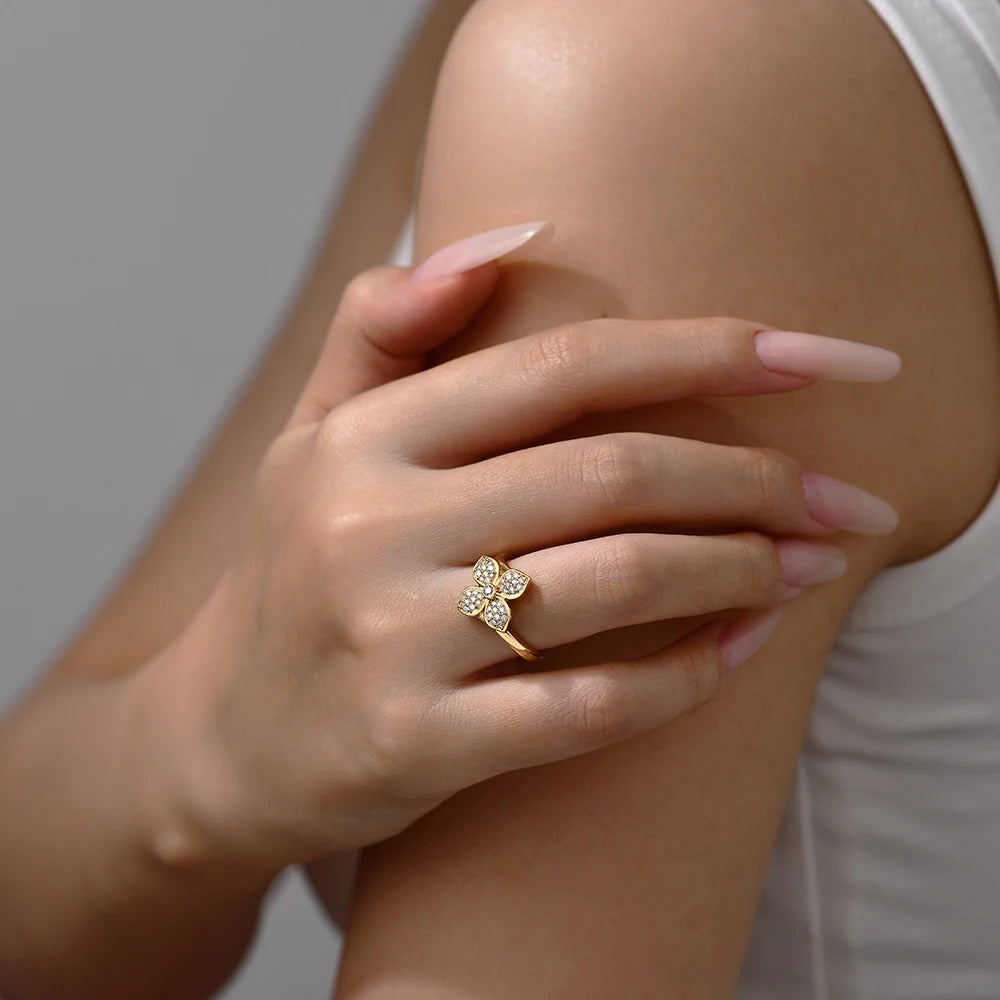 Hand wearing a gold ring with diamonds on a light background