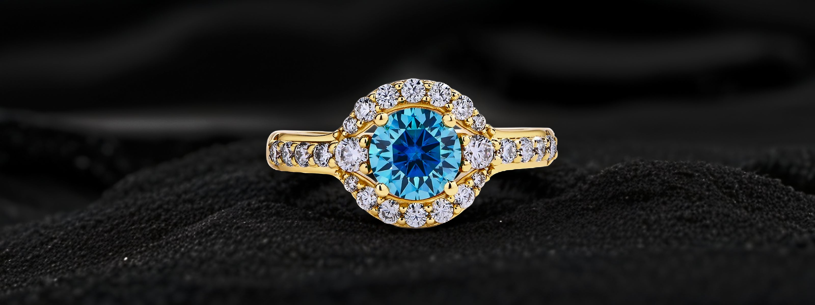 Gold ring with a blue gemstone on a black fabric background