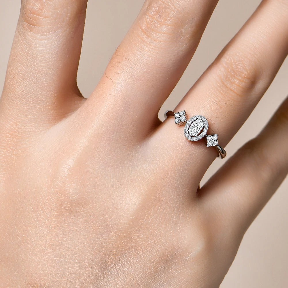 Silver ring with diamonds on a hand against a neutral background