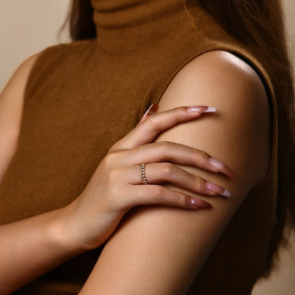 Woman wearing a brown sleeveless top with a close-up of her arm and hand.