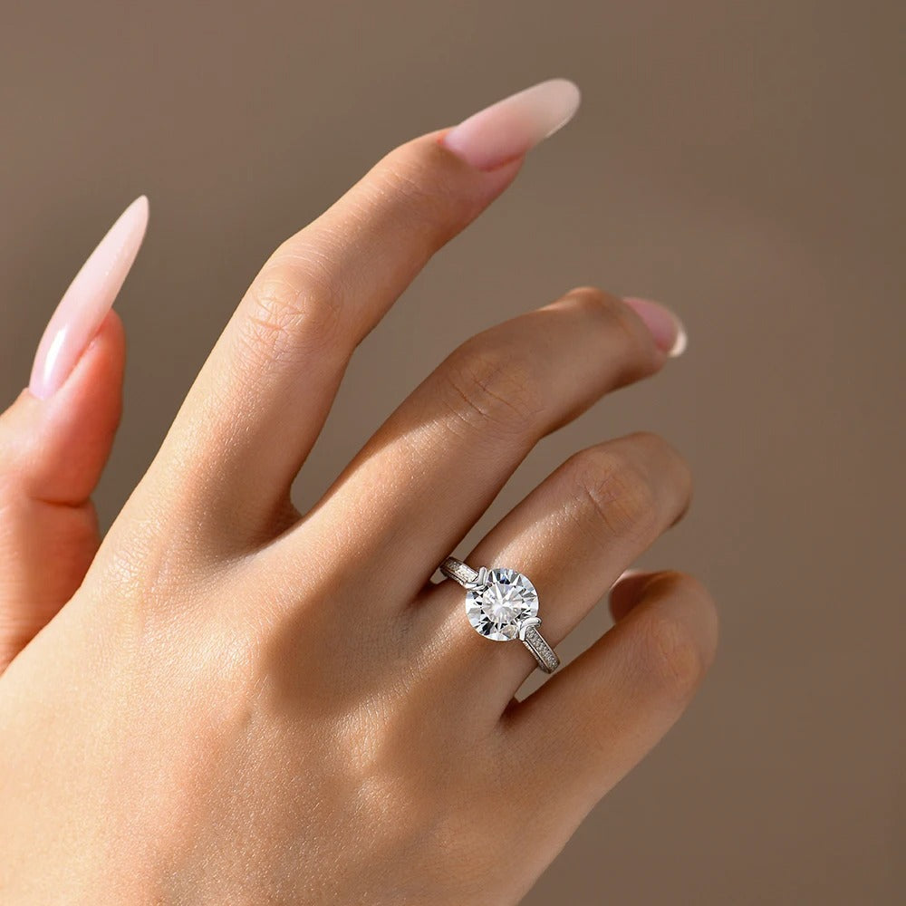 Close-up of a hand wearing a diamond ring on a neutral background