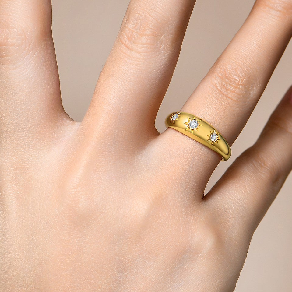 Gold ring with diamonds on a hand against a neutral background