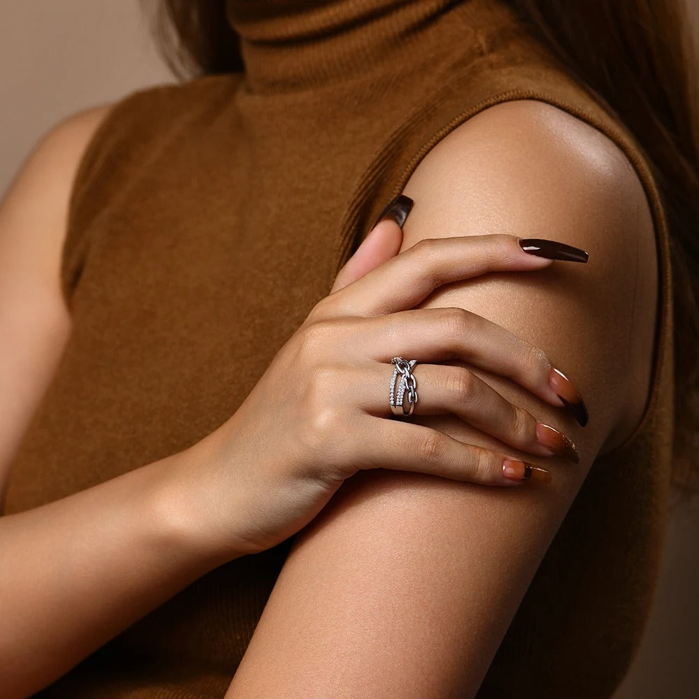 Close-up of a person wearing a ring on their hand against a neutral background