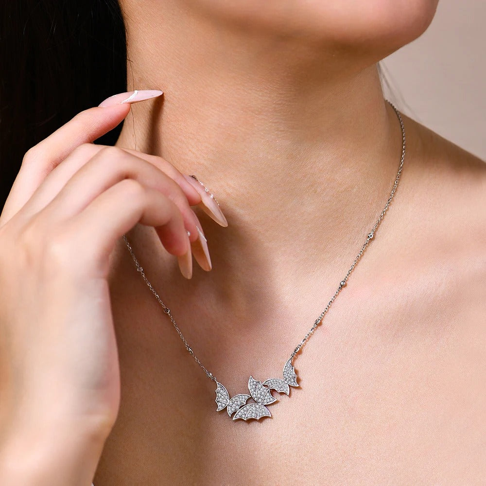 Necklace with butterfly pendant worn by a person, close-up on neck and hand.