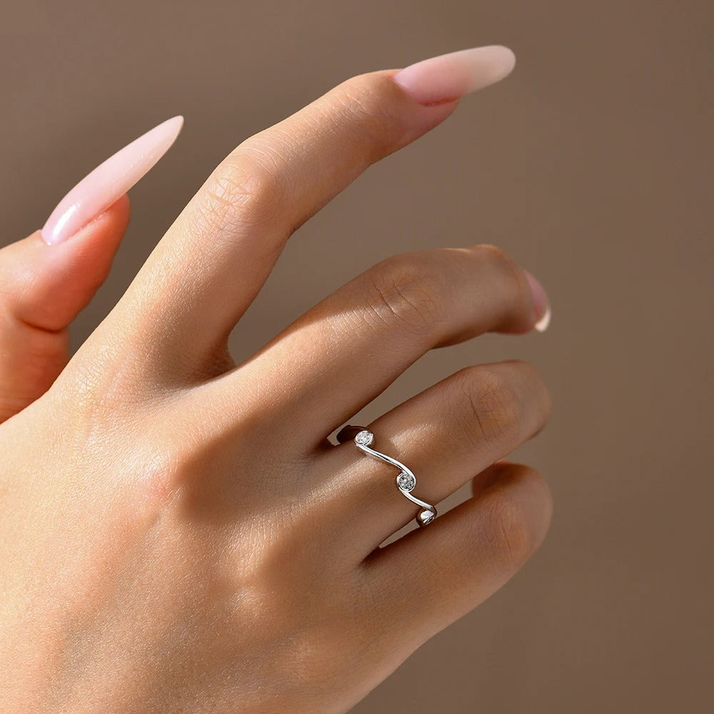 Hand wearing a silver ring with a diamond on a neutral background