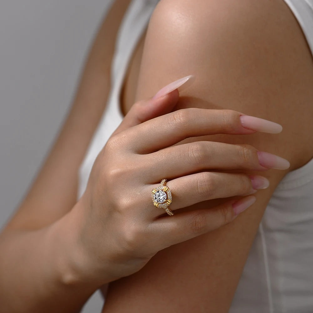 Close-up of a hand wearing a gold ring with a diamond on a neutral background