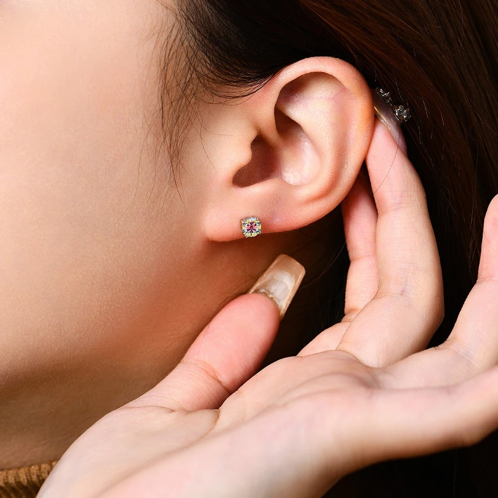 Close-up of an ear with a small earring, held by hands.