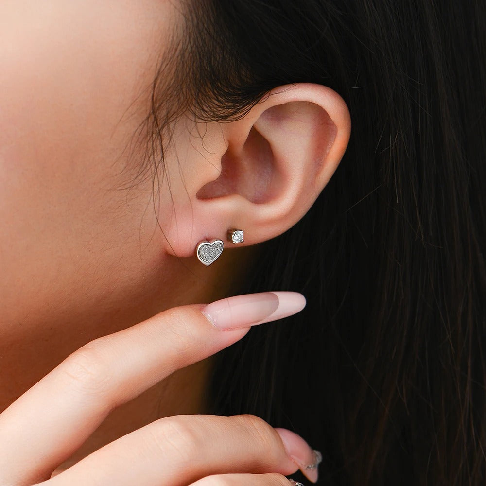 Close-up of an ear wearing a heart-shaped earring with a blurred background