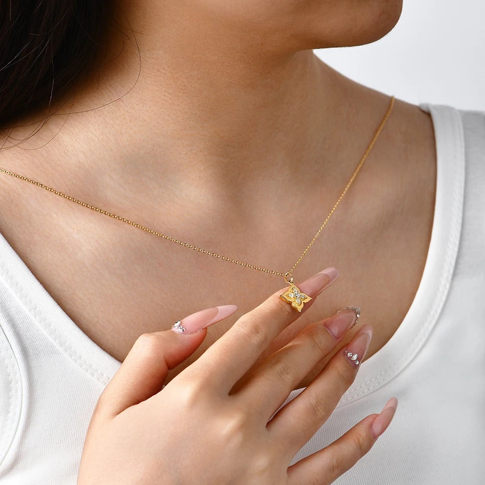Gold necklace with a butterfly pendant worn by a person in a white top.