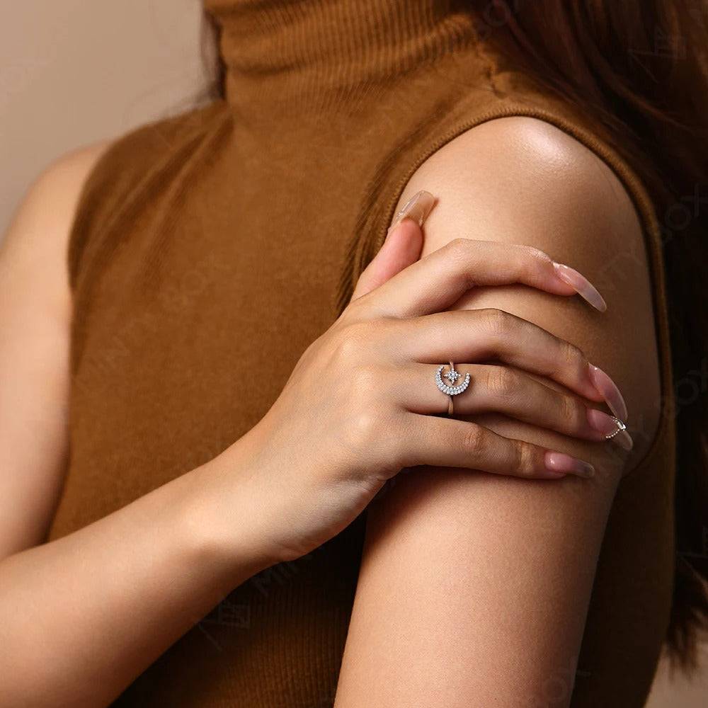 Woman wearing a diamond ring on her finger, holding her arm with a neutral background