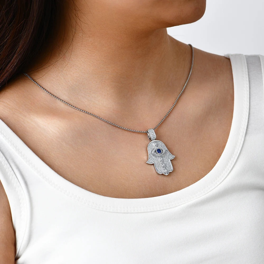 Silver Hamsa hand necklace with a blue stone on a white background