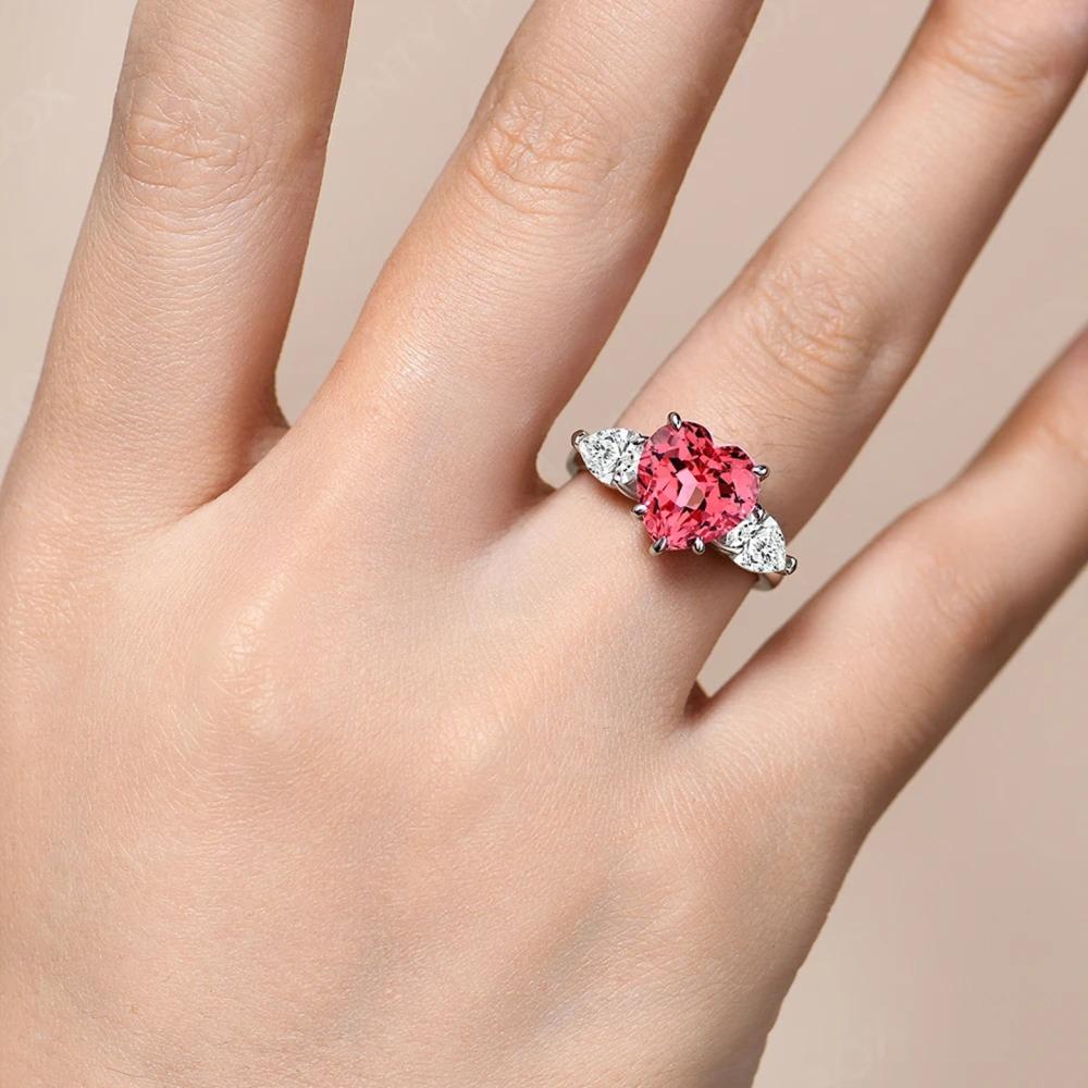 Pink gemstone ring on a hand against a beige background