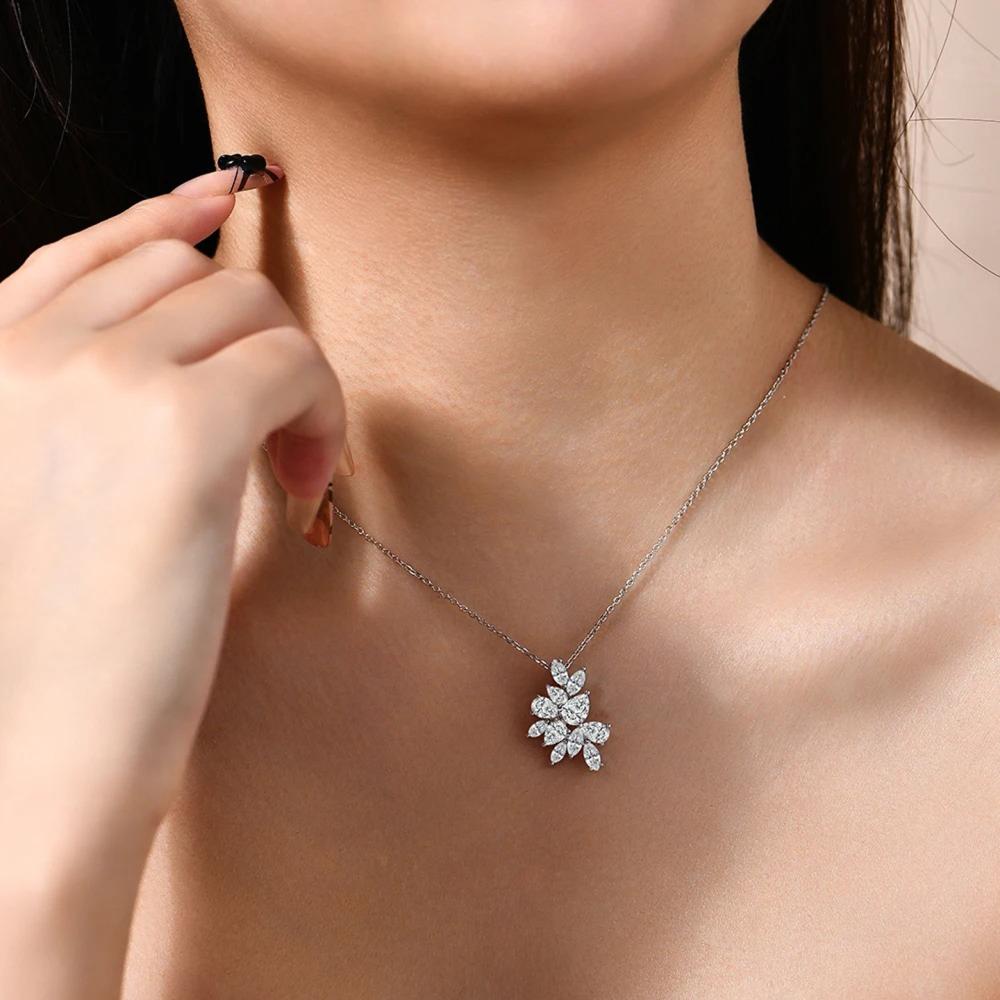 Close-up of a necklace with a floral pendant on a person's neck.