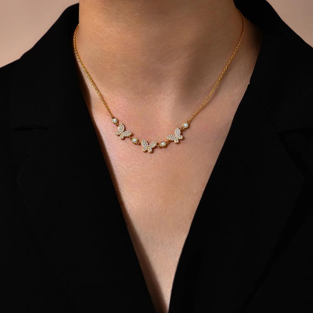 Gold butterfly necklace on a person wearing a black top