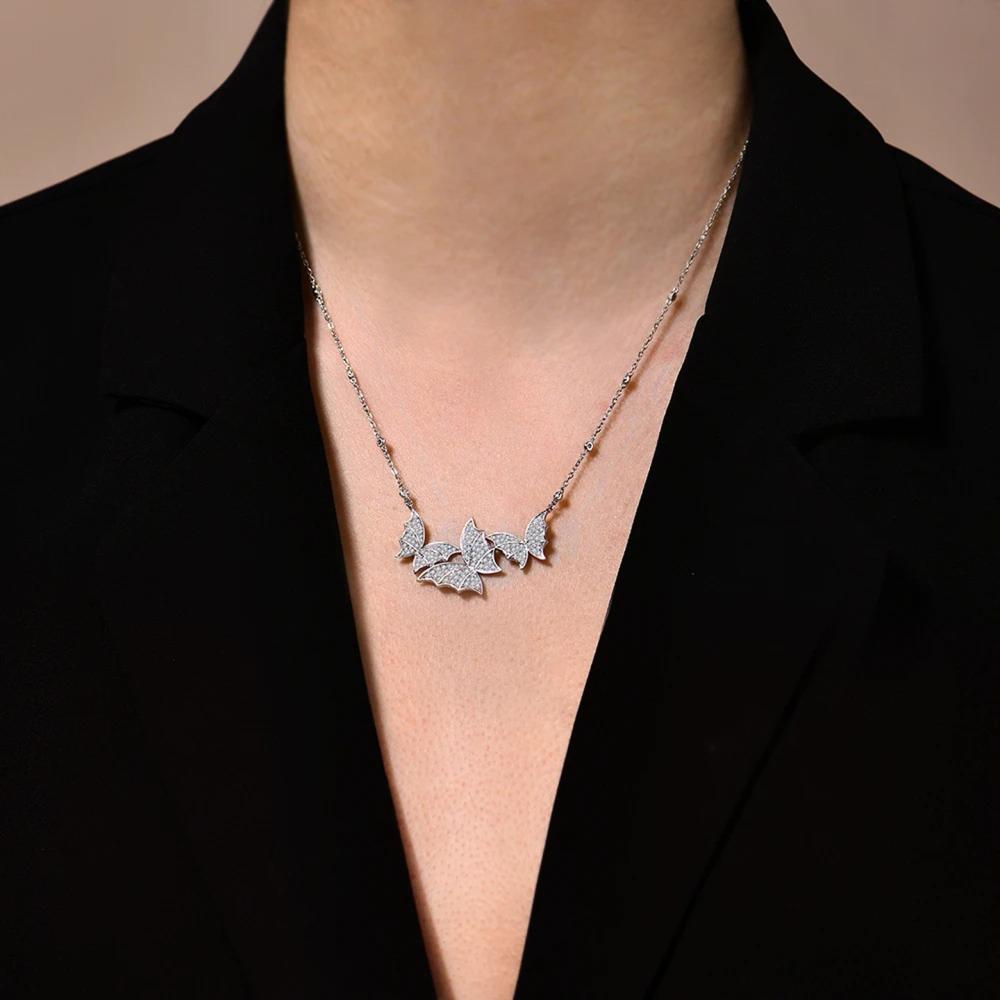 Necklace with butterfly pendants worn by a person against a black background