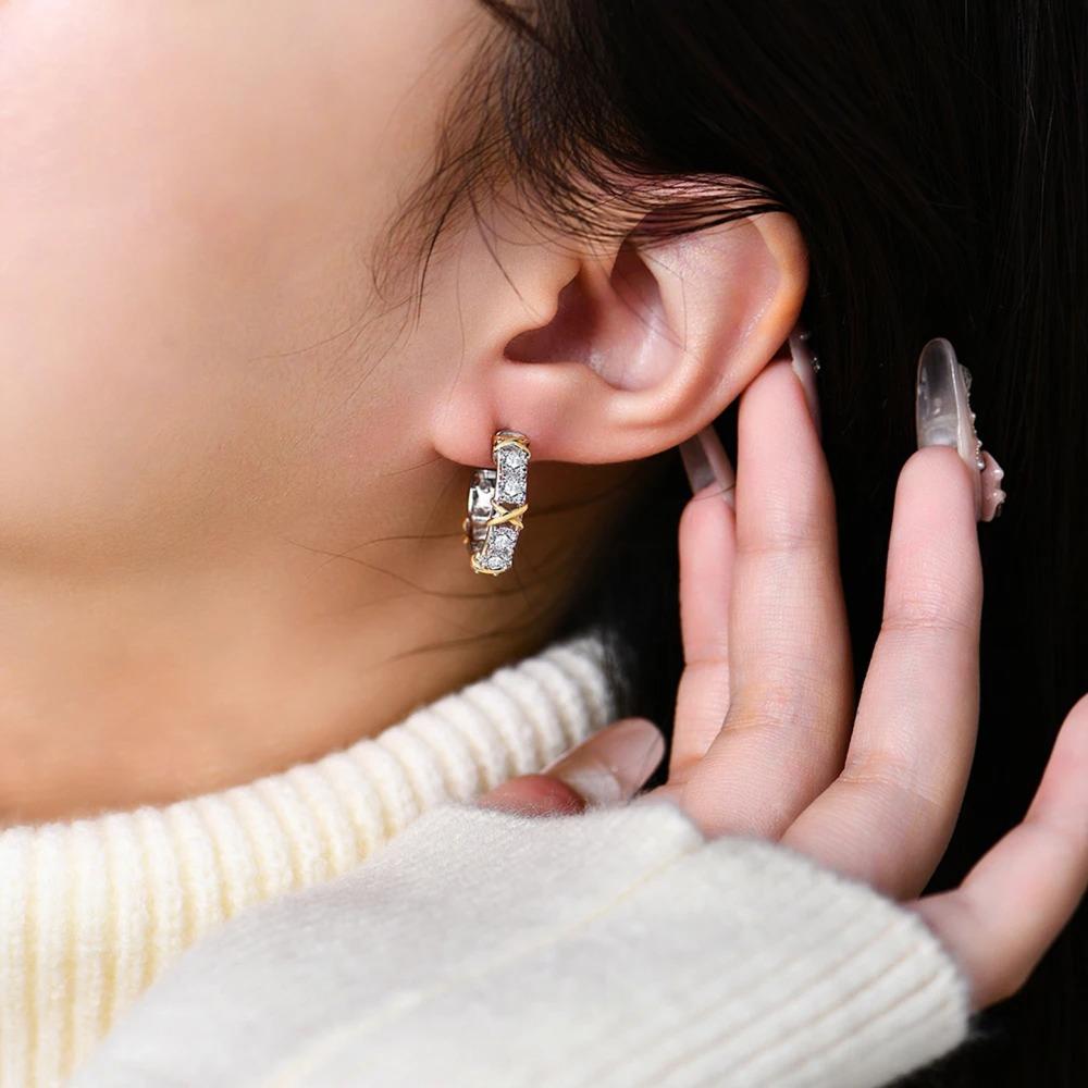 Close-up of an ear wearing a diamond earring with a hand adjusting it.
