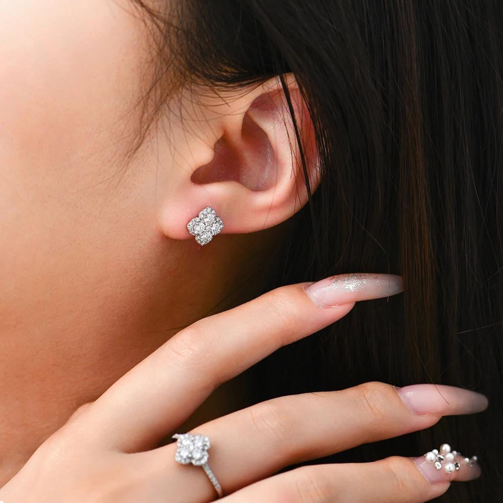 Close-up of a person wearing diamond stud earrings and a ring.