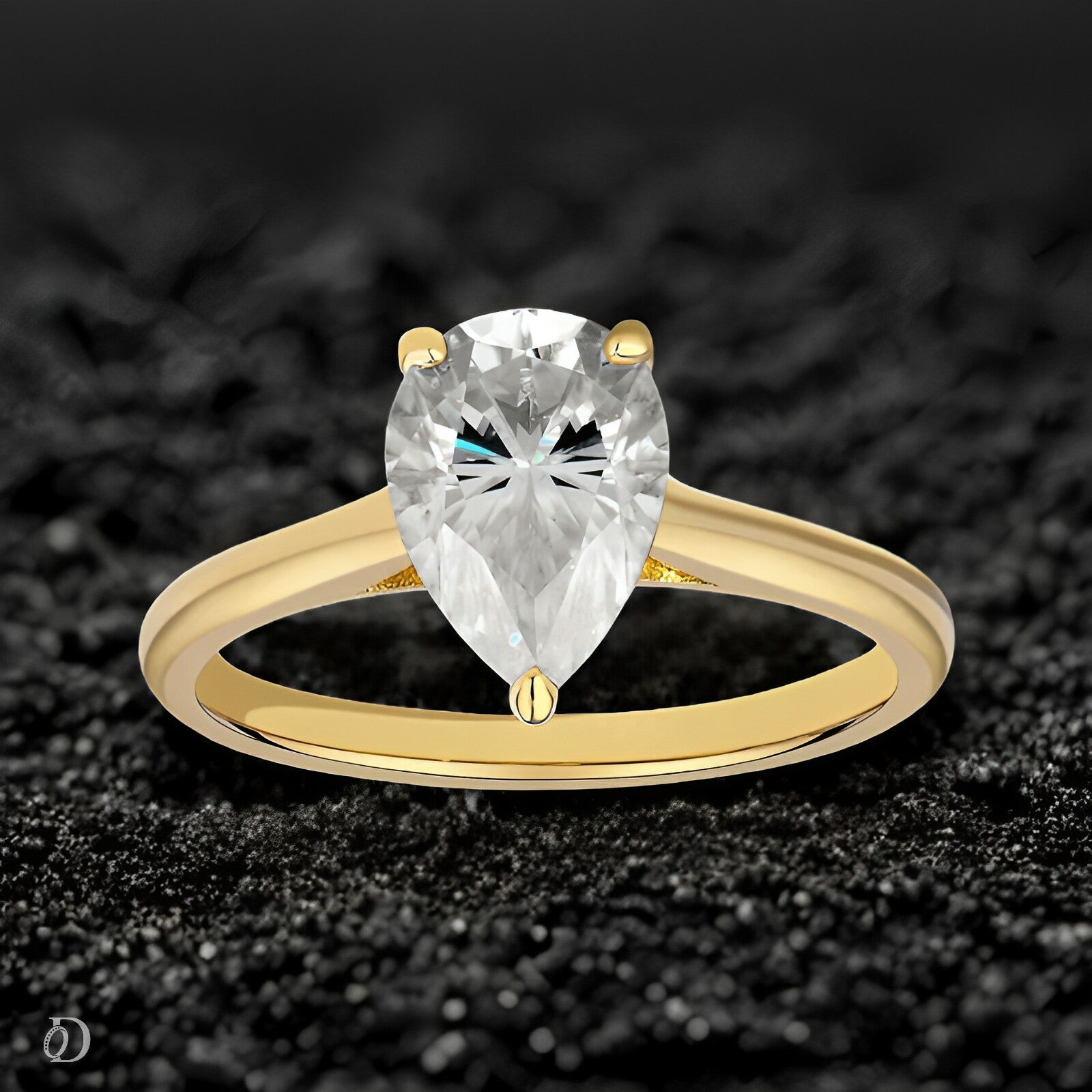 Gold ring with a pear-shaped diamond on a black textured background