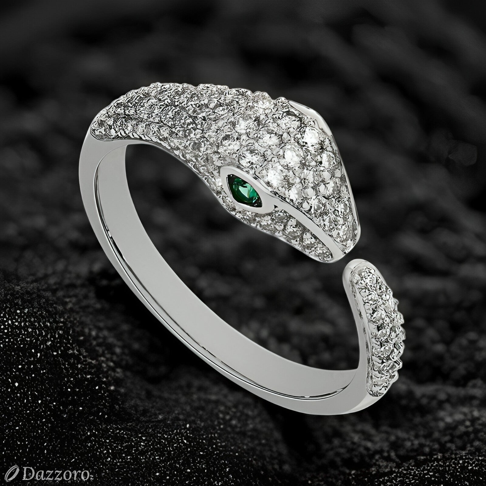 Silver snake-shaped ring with a green gemstone on a dark textured background, branded 'Dazzzoro'.