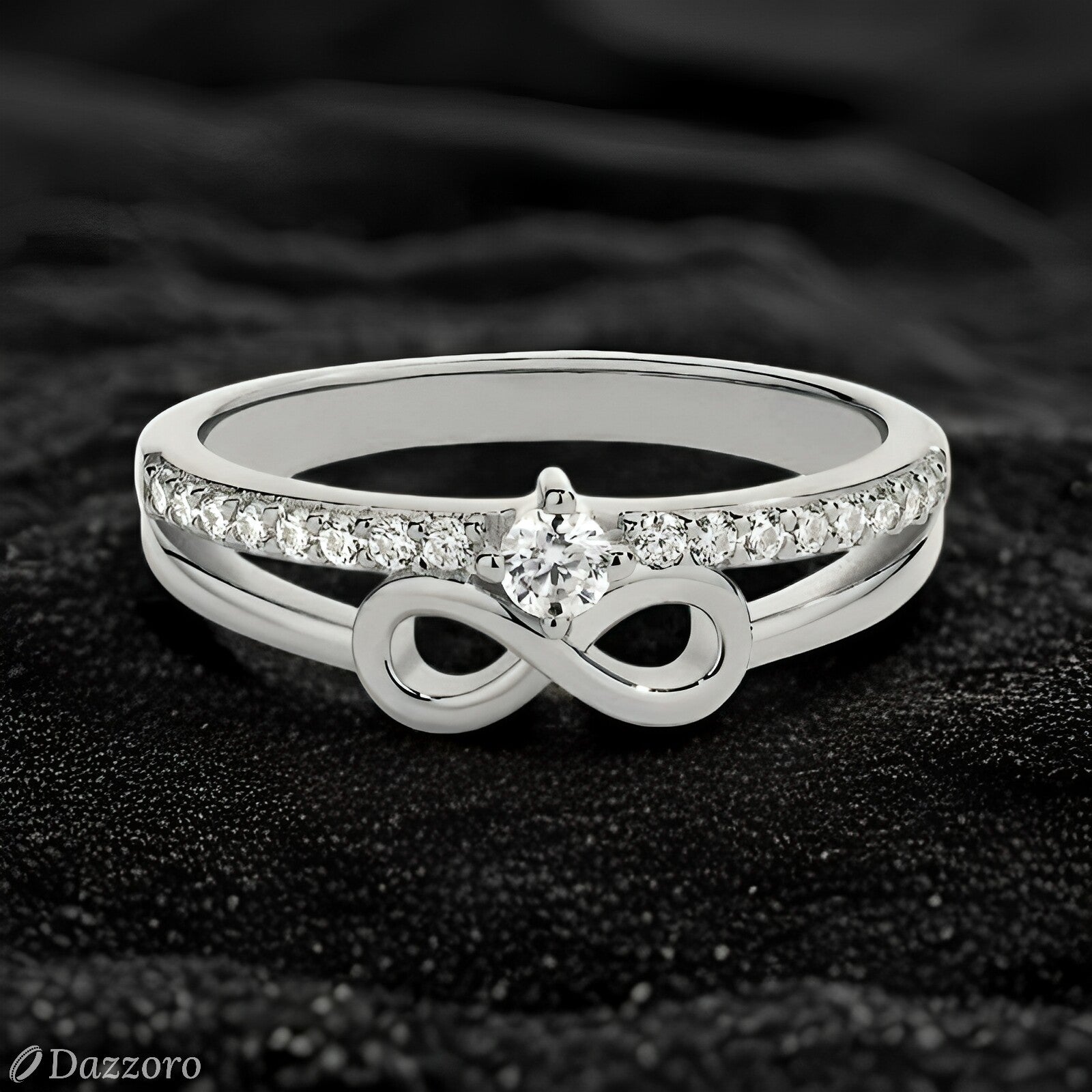 Silver ring with infinity symbol and diamonds on a dark textured background, Dazzzoro brand visible.