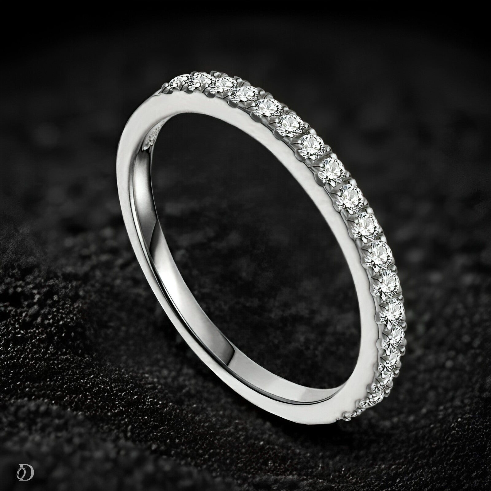 Silver ring with small diamonds on a dark textured background