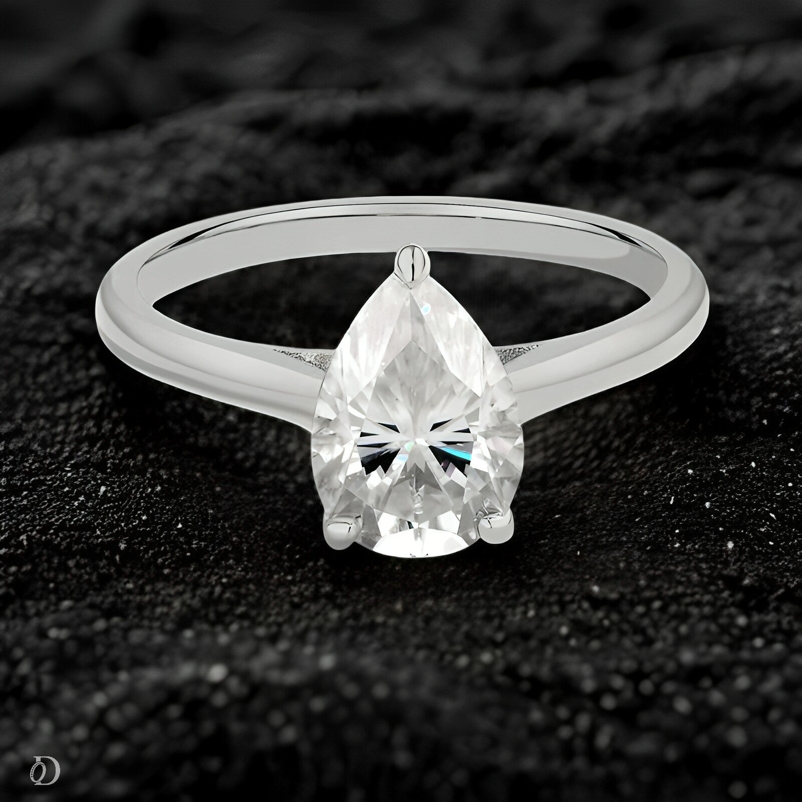 Silver ring with a pear-shaped diamond on a textured black background