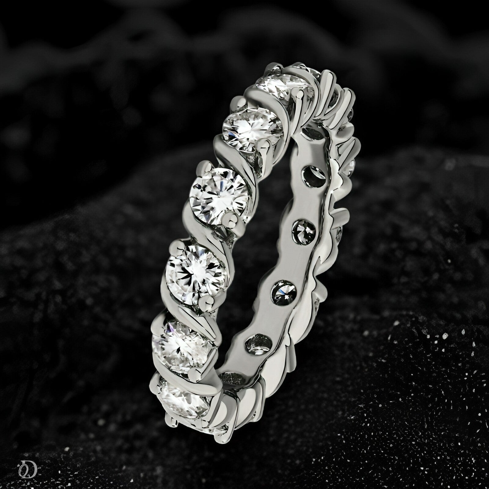 Silver ring with embedded diamonds on a dark textured background