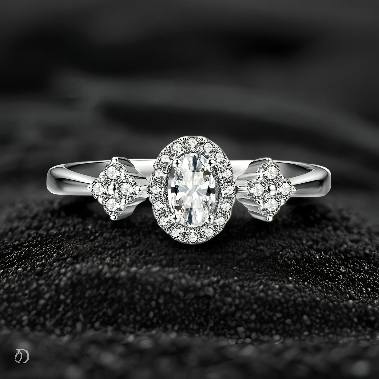 Silver ring with a central diamond and smaller diamonds on a textured black surface
