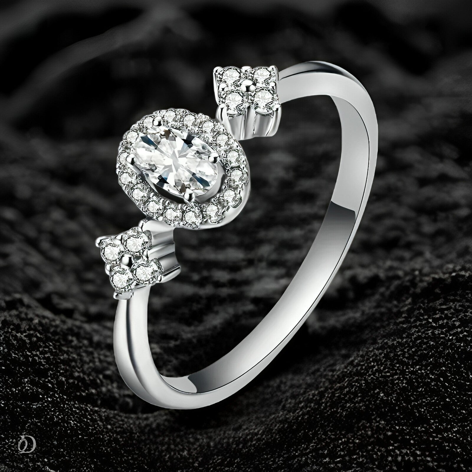 Silver ring with a large central gemstone and smaller stones on a dark textured background