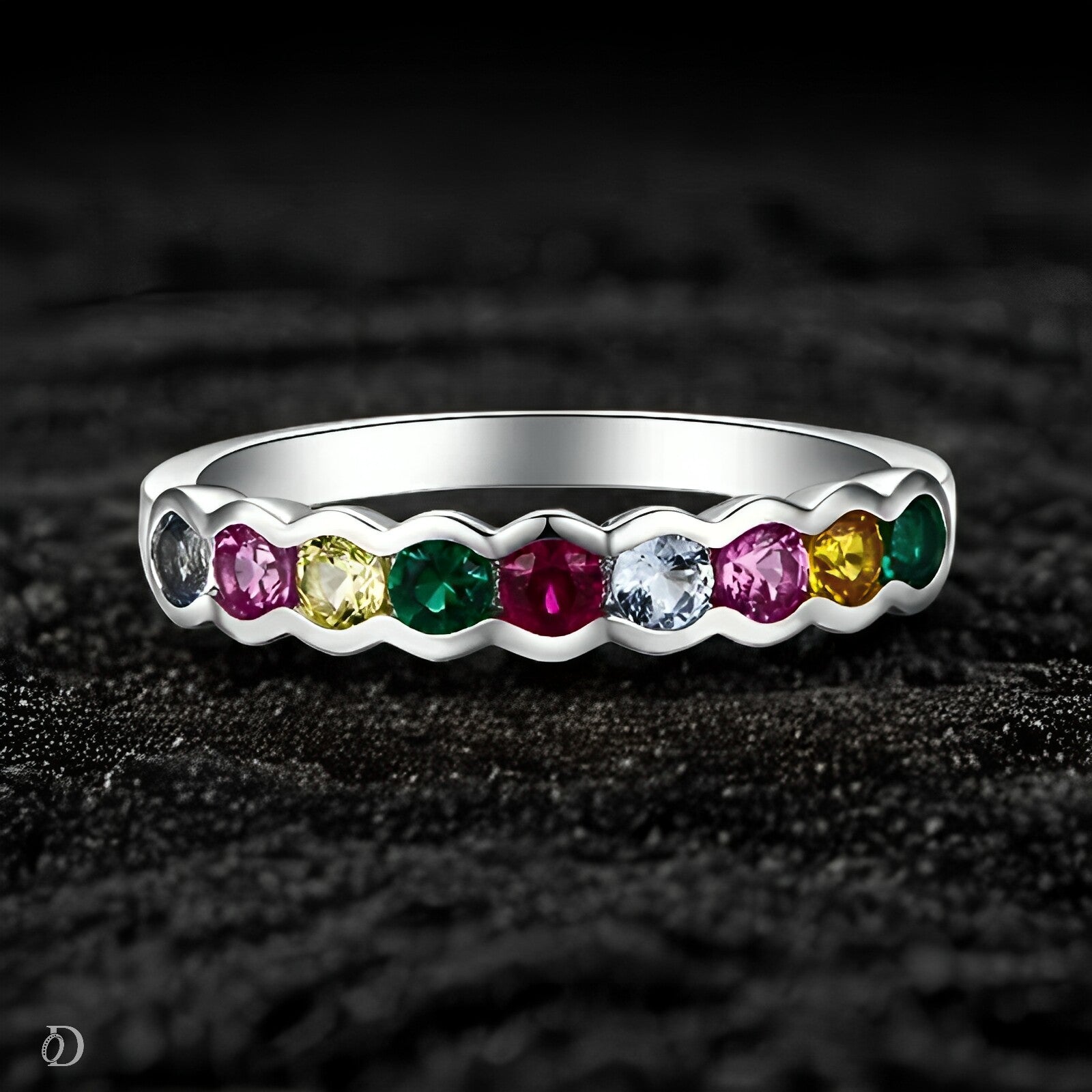 Silver ring with colorful gemstones on a dark textured background
