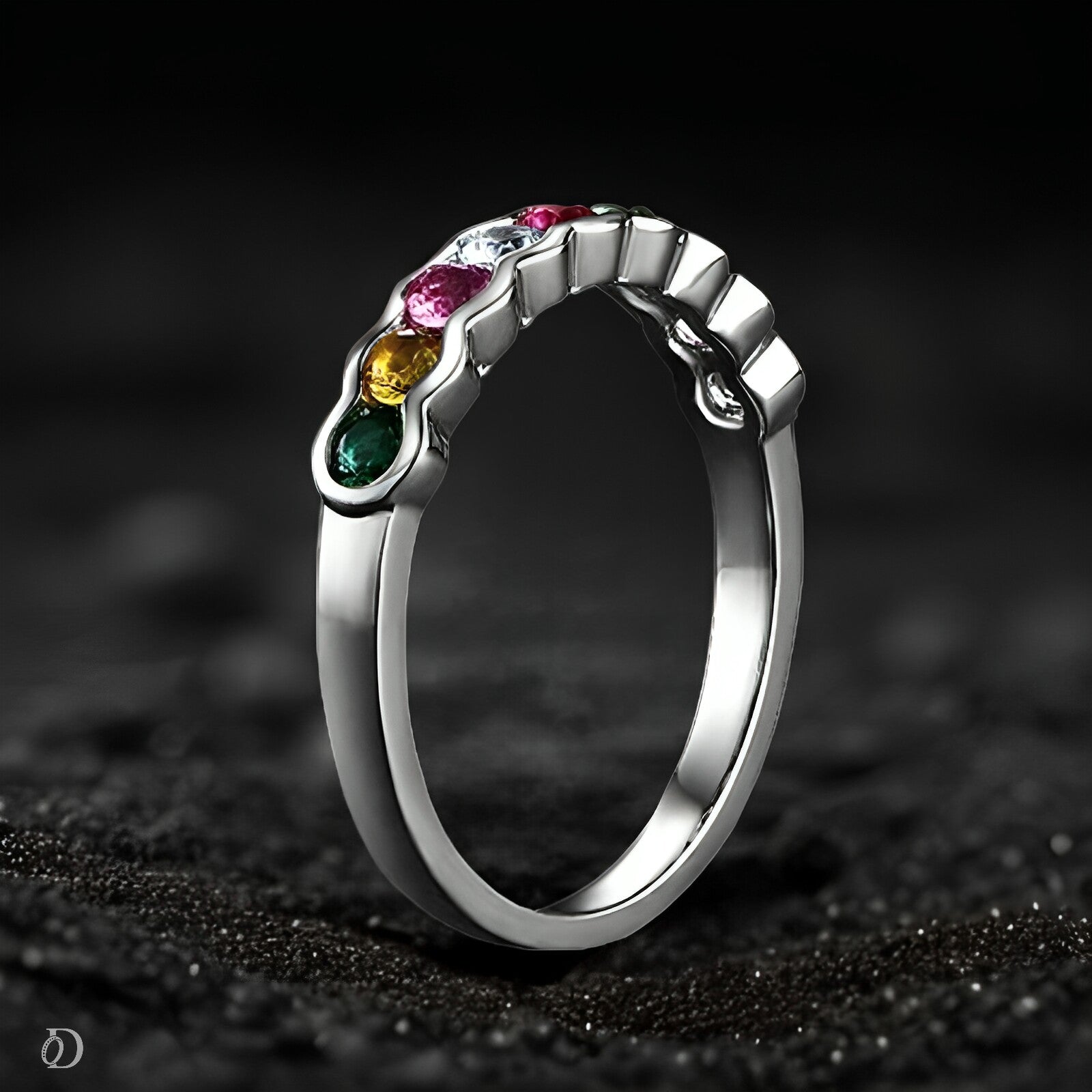 Silver ring with multicolored gemstones on a dark textured background