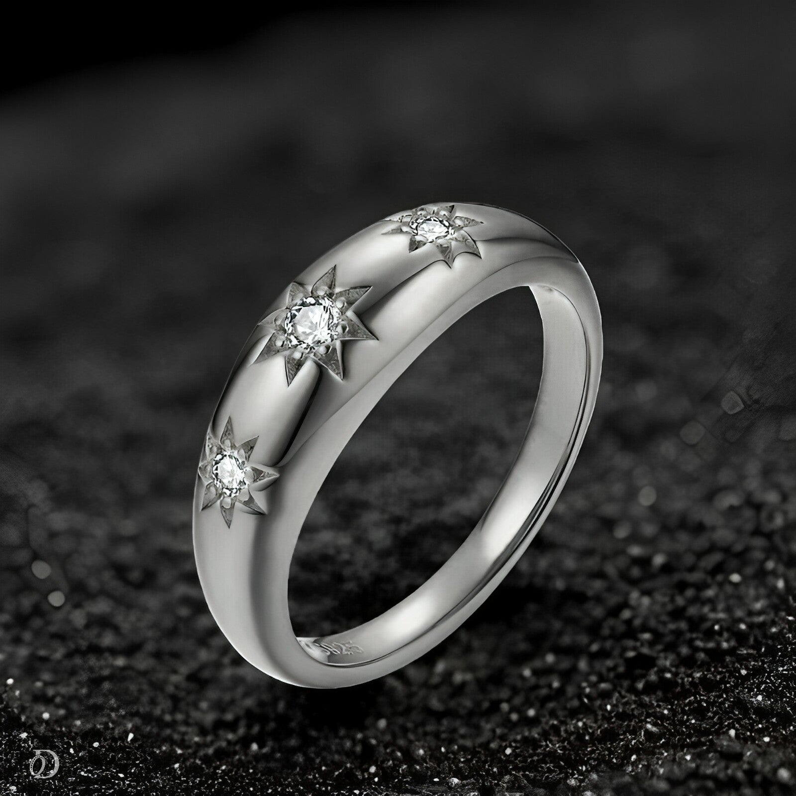 Silver ring with star-shaped gemstones on a dark textured background